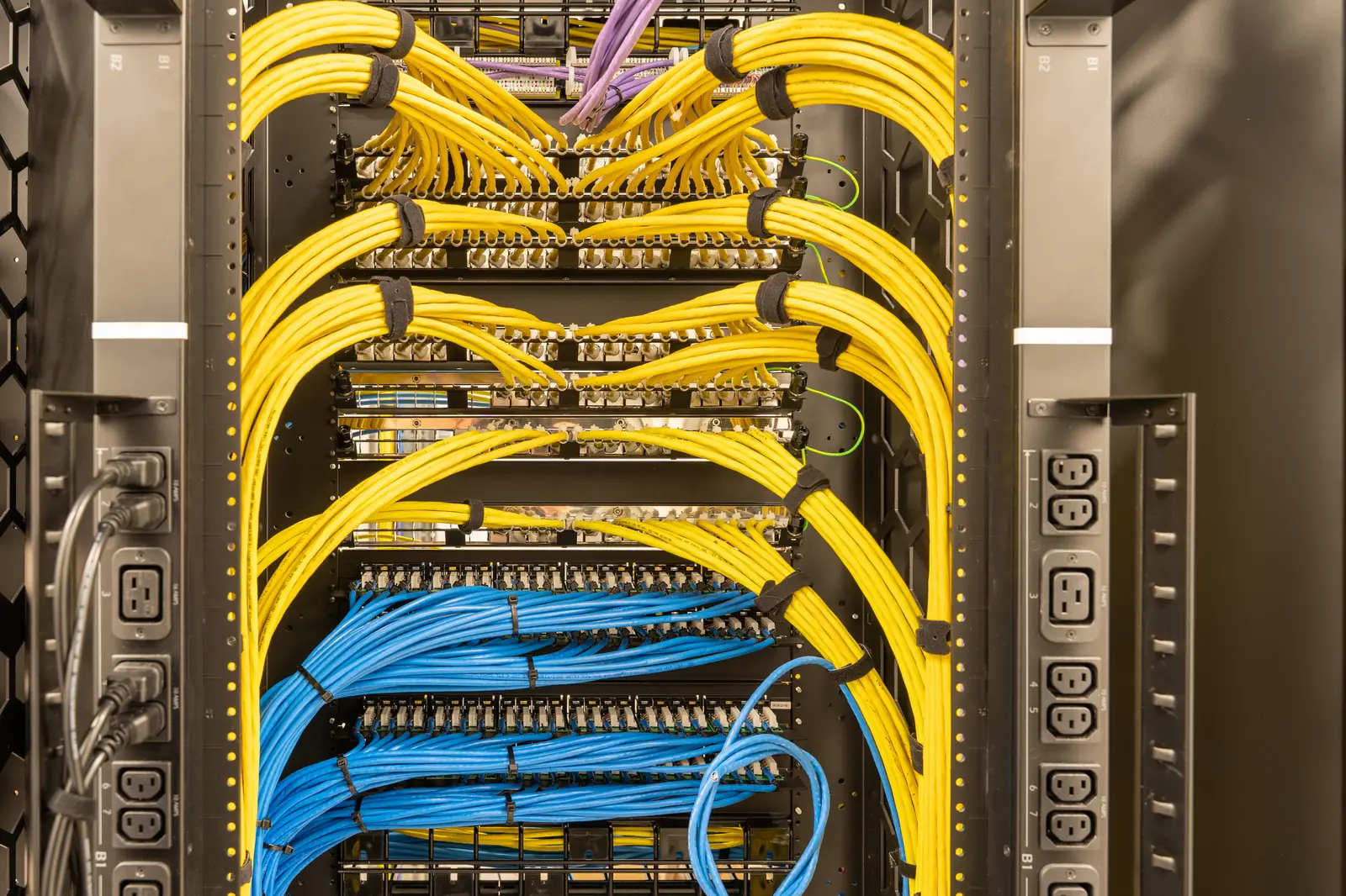 Organized yellow and blue patch leads in a network rack.